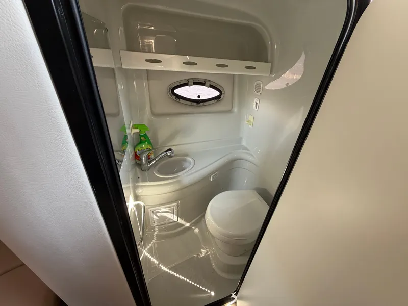 Slide: The Image of The image shows the bathroom of a 2018 Crownline 264 CR with a toilet and sink. - 14