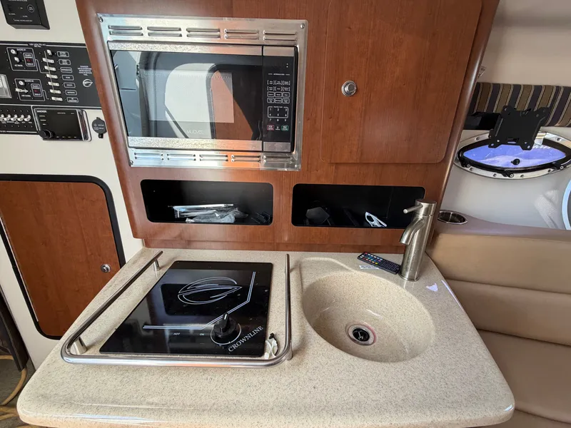 Slide: The Image of The galley of a 2018 Crownline 264 CR with a microwave, stove, and sink. - 9