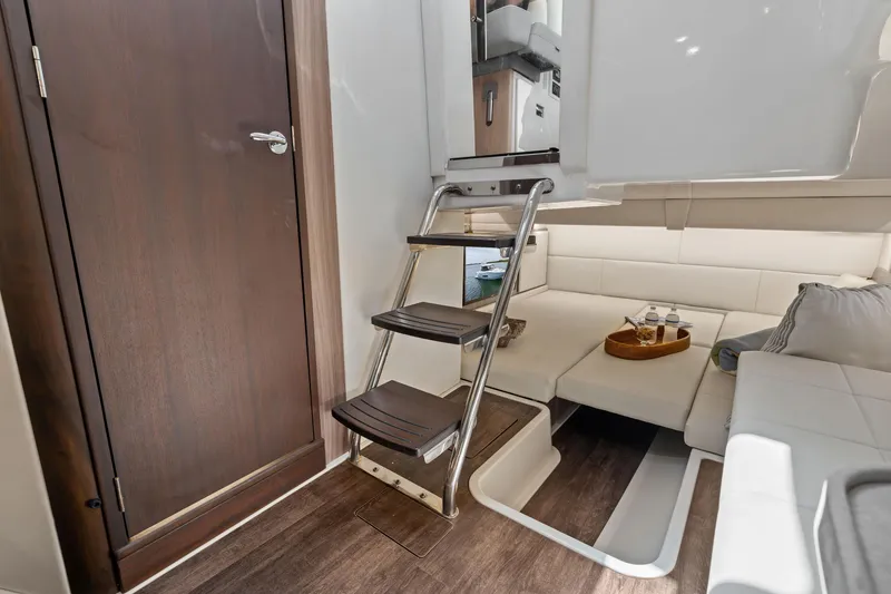 Slide: The Image of Interior of a 2022 Regal boat featuring a cozy seating area and wooden steps. - 23