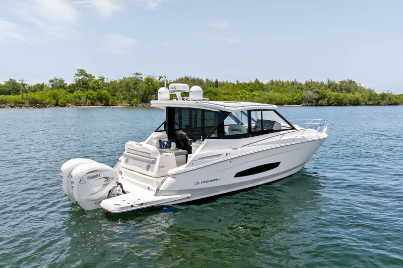 Slide: The Image of 2022 Regal boat with Yamaha engine on calm water, surrounded by lush greenery. - 2