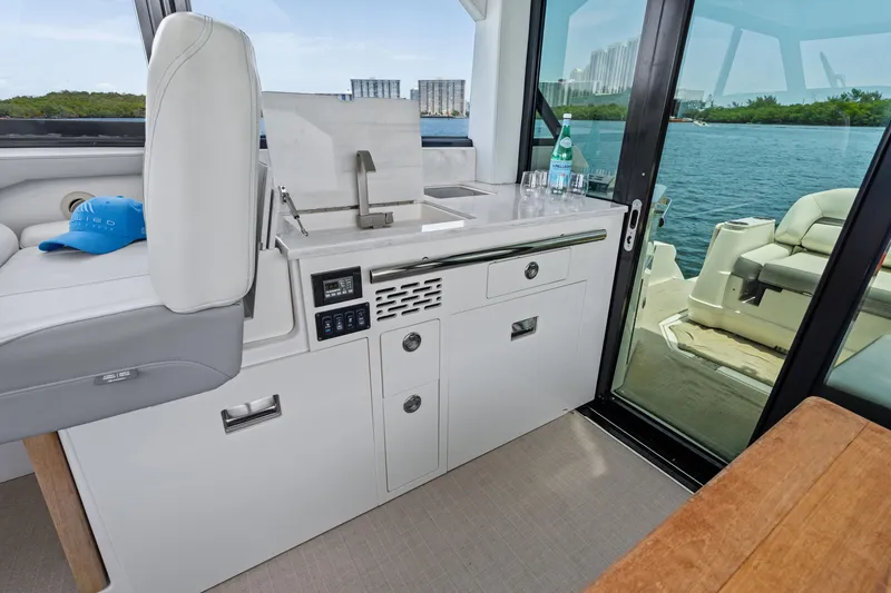 Slide: The Image of Luxurious 2022 Regal boat interior with kitchenette, sink, and seating, overlooking serene water view. - 11