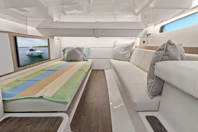 Slide: The Image of Luxurious 2022 Regal boat interior with cozy seating, striped bedding, and a scenic window view. - 31