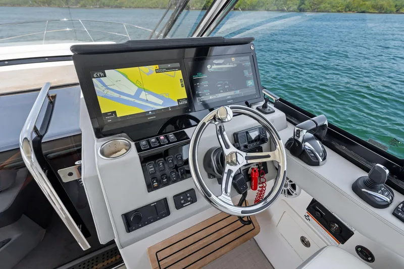 Slide: The Image of 2022 Regal boat helm with navigation screens and steering wheel on a lake. - 8