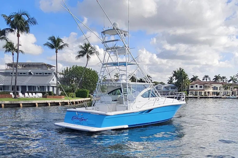 Slide: The Image of 2003 Tiara Yachts 3800 Open in a scenic waterfront setting with palm trees. - 1