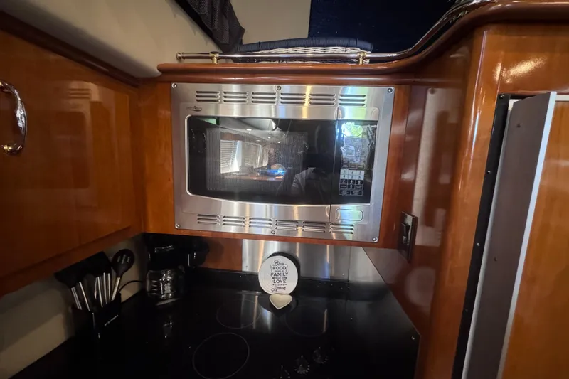 Slide: The Image of 2004 Carver 466 Motor Yacht kitchen with microwave and wooden cabinetry. - 32