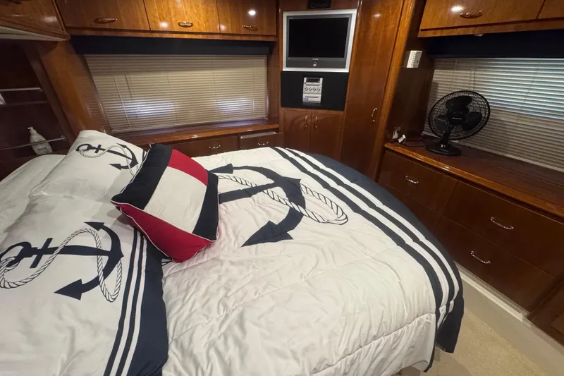 Slide: The Image of Luxurious 2004 Carver 466 Motor Yacht bedroom with nautical-themed bedding and wood cabinetry. - 22