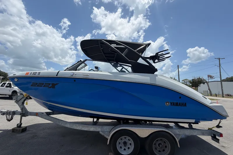 Slide: The Image of 2024 Yamaha Boats 222XD in blue on a trailer under a cloudy sky. - 6