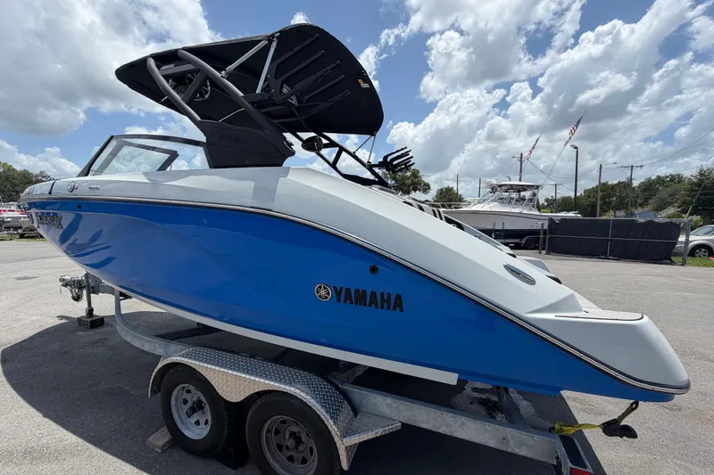 Slide: The Image of 2024 Yamaha Boats 222XD in blue and white on a trailer under a cloudy sky. - 5