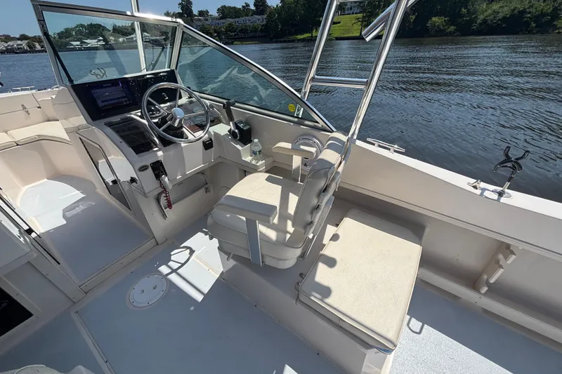Slide: The Image of 1999 Grady-White Tournament 225 boat interior with steering wheel and seating by the water. - 22