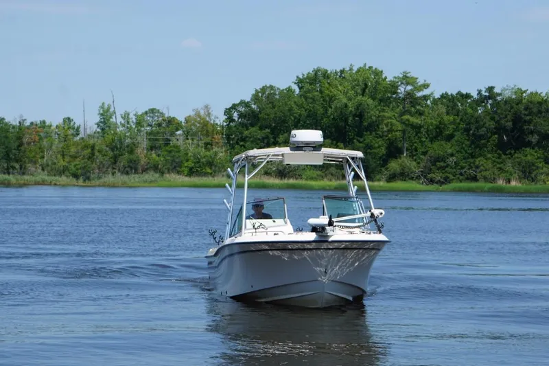 Slide: The Image of 1999 Grady-White Tournament 225 boat cruising on a serene lake with lush green trees. - 3