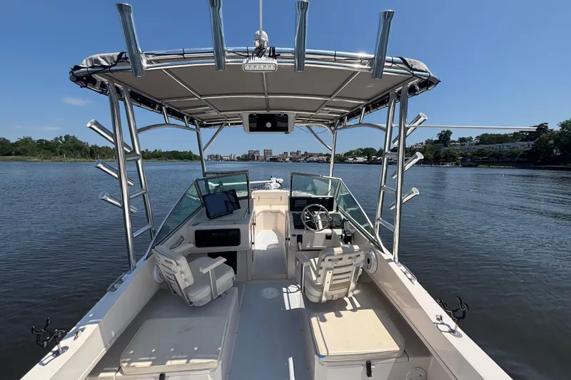Slide: The Image of 1999 Grady-White Tournament 225 boat on calm water, featuring spacious seating and fishing rod holders. - 20