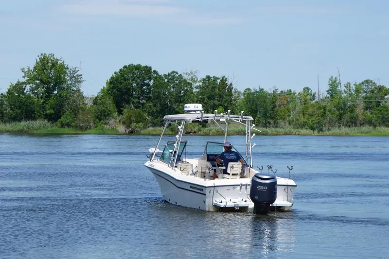 Slide: The Image of 1999 Grady-White Tournament 225 boat cruising on a serene lake with lush greenery. - 7