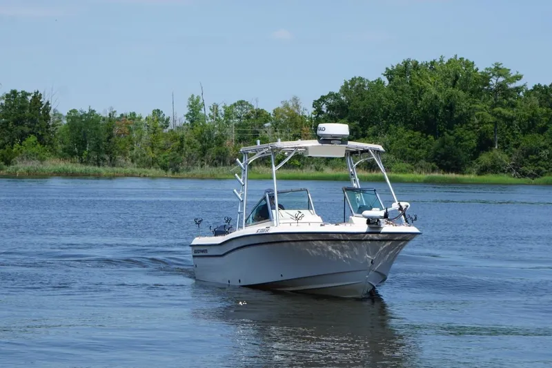 Slide: The Image of 1999 Grady-White Tournament 225 boat cruising on a serene lake with lush greenery. - 5