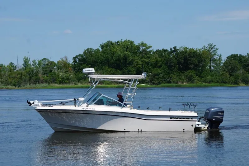Slide: The Image of 1999 Grady-White Tournament 225 boat on calm water with lush green background. - 12