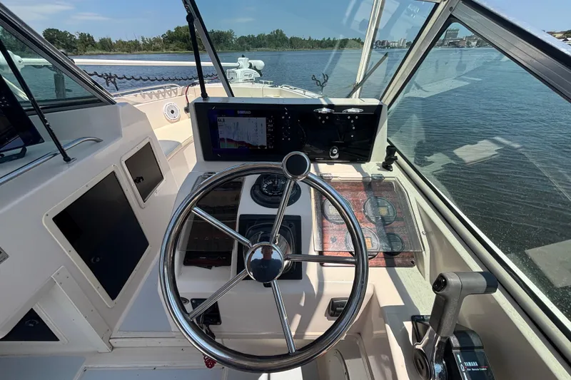 Slide: The Image of 1999 Grady-White Tournament 225 boat cockpit with steering wheel and navigation equipment. - 13