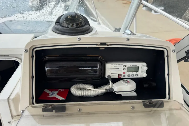 Slide: The Image of 1999 Boston Whaler 21 Conquest dashboard with compass, radio, and storage compartment. - 13