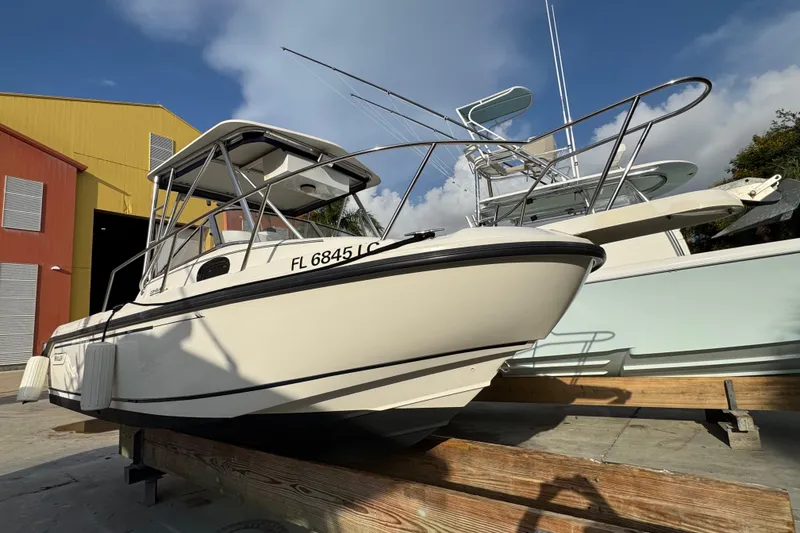 The Image of 1999 Boston Whaler 21 Conquest boat docked near colorful warehouse under blue sky. - 0