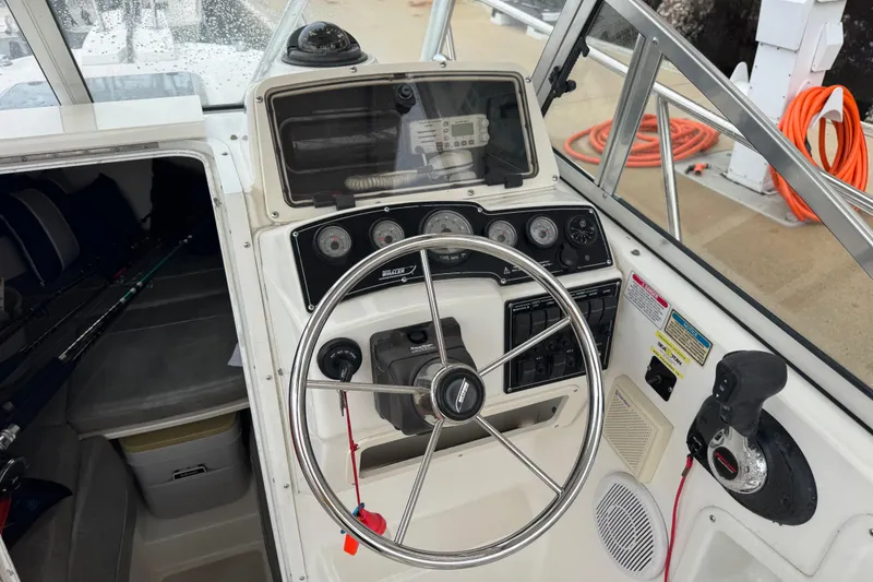 Slide: The Image of 1999 Boston Whaler 21 Conquest boat helm with steering wheel and control panel. - 12