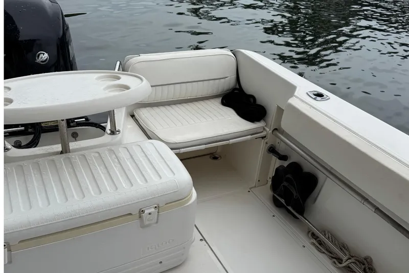 Slide: The Image of 1999 Boston Whaler 21 Conquest boat interior with seating and table by the water. - 11