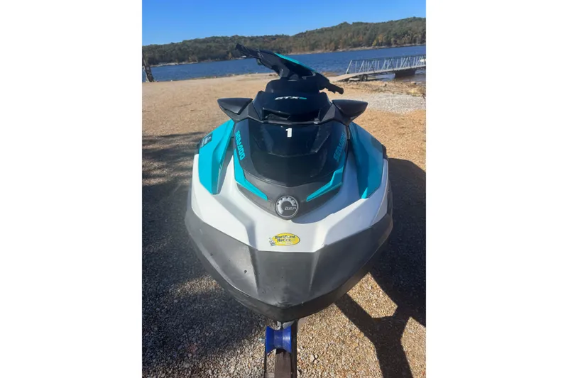 Slide: The Image of 2022 Sea-Doo GTI SE 130 jet ski parked by a scenic lake. - 2