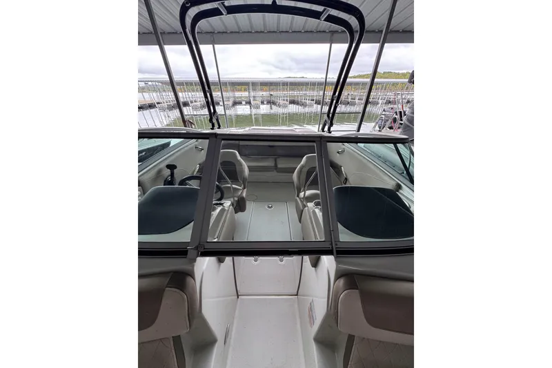 Slide: The Image of 2019 Crownline 215 SS boat interior with seating and steering wheel, docked at marina. - 12