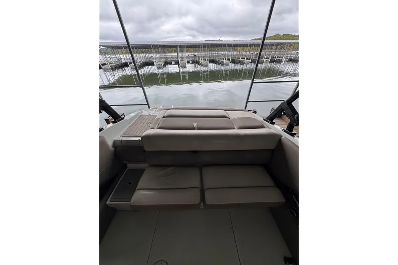 Slide: The Image of 2019 Crownline 215 SS boat interior with cushioned seating, overlooking a calm marina. - 10