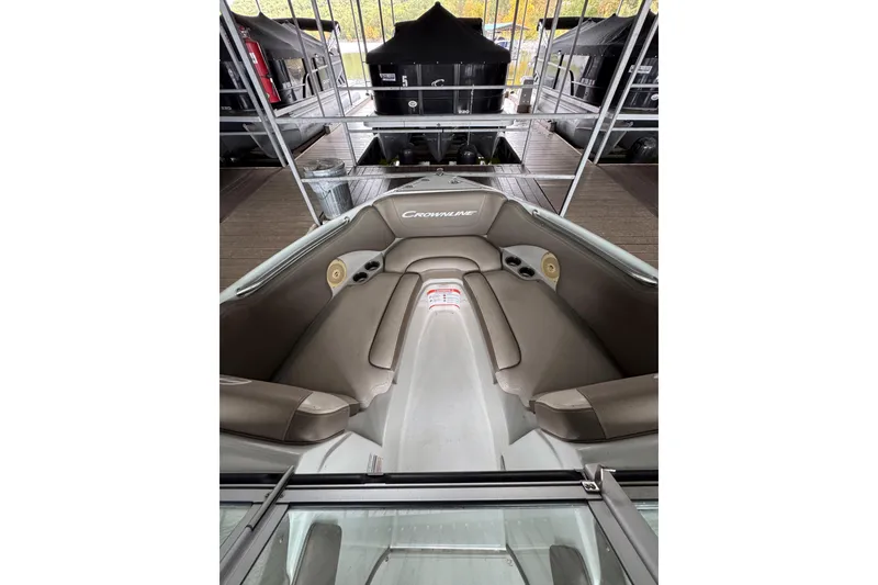 Slide: The Image of 2019 Crownline 215 SS boat interior with cushioned seating in a marina setting. - 11
