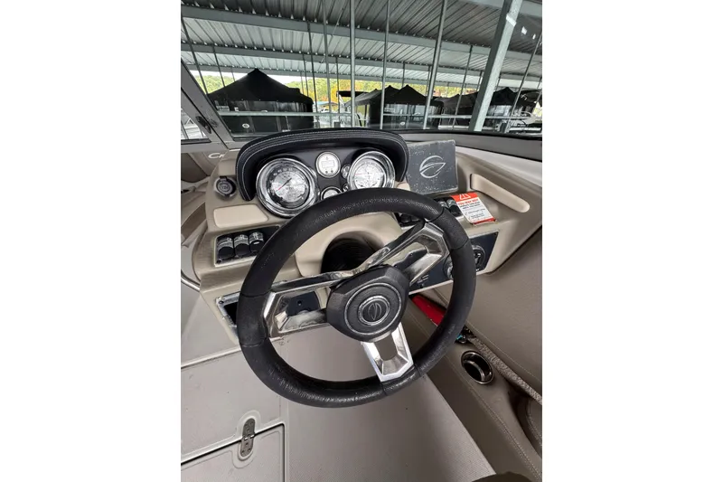 Slide: The Image of Steering wheel and dashboard of a 2019 Crownline 215 SS boat in a covered marina. - 8