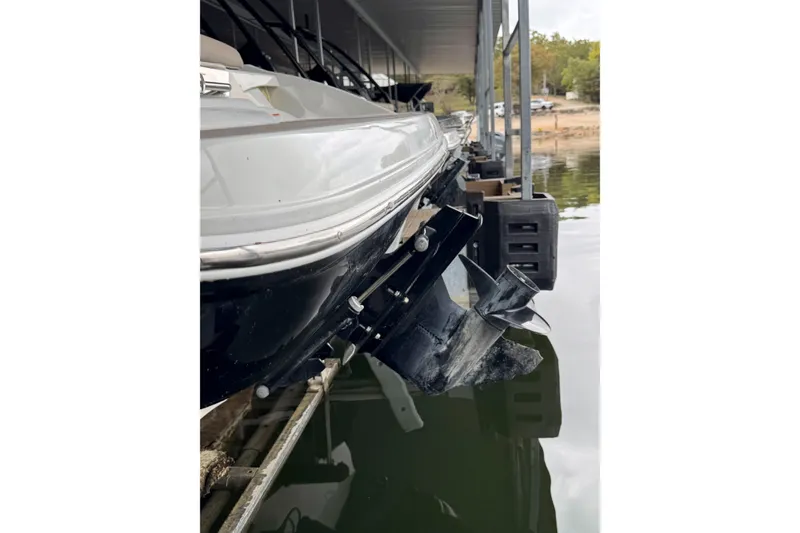 Slide: The Image of 2019 Crownline 215 SS boat docked, showing stern and propeller in water. - 17