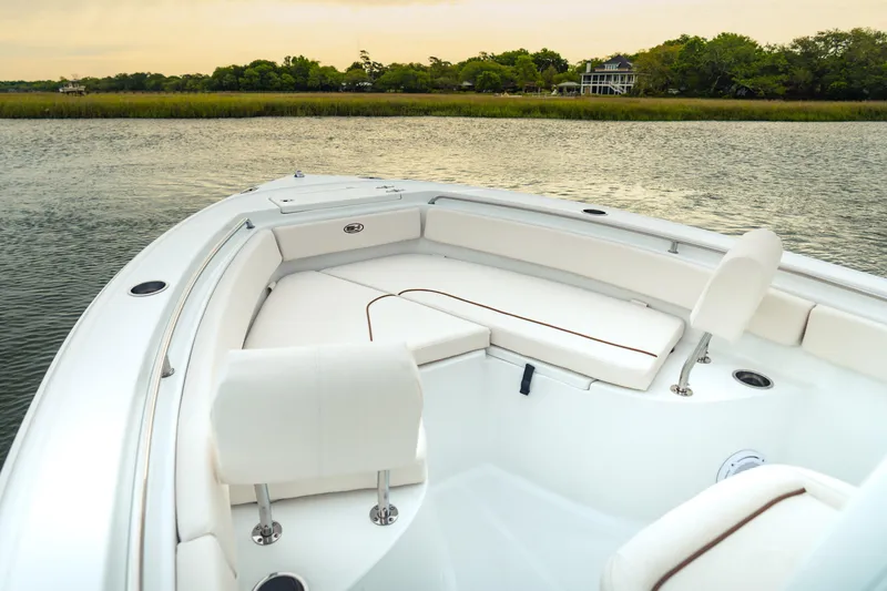 Slide: The Image of 2027 Sea Hunt Ultra 219 boat interior with white seating, on calm water. - 39
