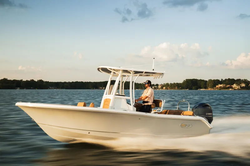 Slide: The Image of 2027 Sea Hunt Ultra 219 boat cruising on a serene lake at sunset. - 30