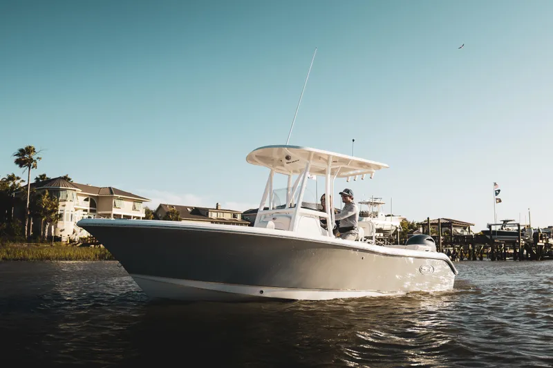 Slide: The Image of 2027 Sea Hunt Ultra 219 boat cruising near waterfront homes under clear blue sky. - 33