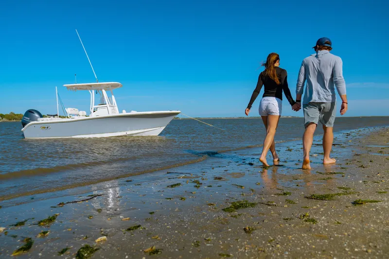 Slide: The Image of Couple walking on beach near Sea Hunt Ultra 219 boat, 2027 model. - 32