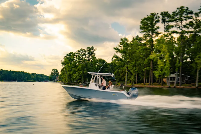 Slide: The Image of 2027 Sea Hunt Ultra 219 boat cruising on a scenic lake with lush trees. - 41