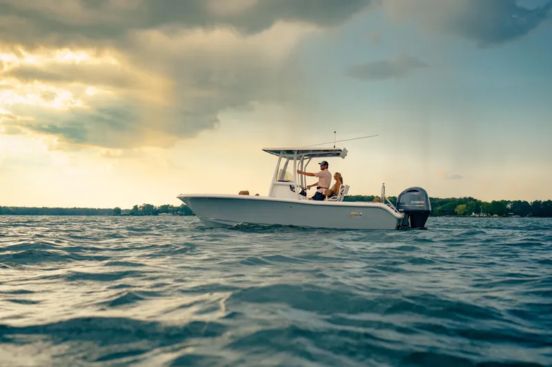 Slide: The Image of 2027 Sea Hunt Ultra 219 boat cruising on a serene lake under a dramatic sky. - 31
