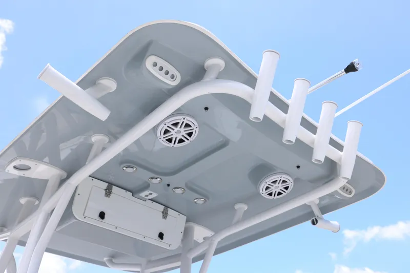Slide: The Image of T-top of 2027 Sea Hunt Ultra 219 boat with rod holders and speakers against blue sky. - 13