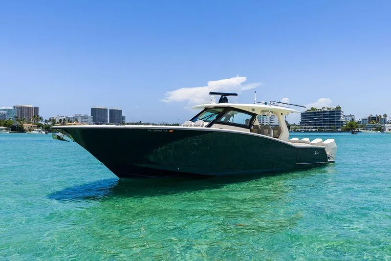 Slide: The Image of 2021 Scout 425 LXF boat on clear turquoise water with city skyline background. - 2