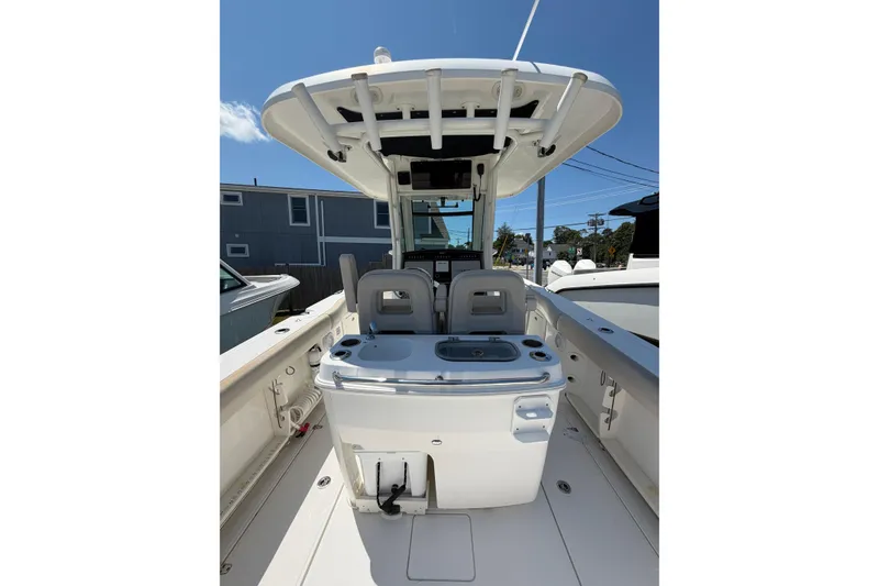Slide: The Image of 2016 Boston Whaler 280 Outrage boat interior with seating and console under clear blue sky. - 6