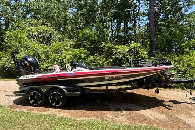 The Image of 2022 Skeeter FXR21 Limited boat on trailer, parked in a wooded area. - 0