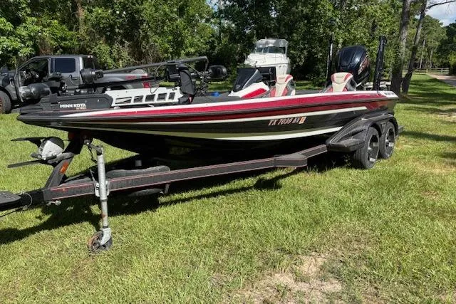 Slide: The Image of 2022 Skeeter FXR21 Limited boat on trailer, parked on grass, surrounded by trees. - 4