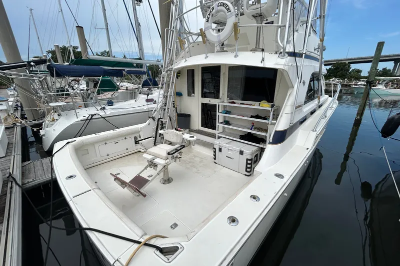 Slide: The Image of 1990 Bertram 37 Convertible yacht docked, featuring spacious deck and fishing chair. - 6
