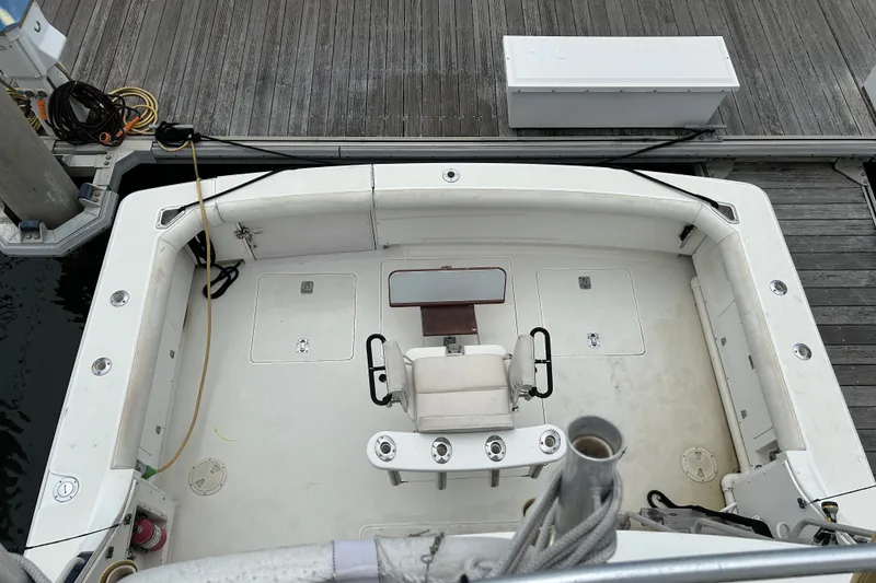 Slide: The Image of 1990 Bertram 37 Convertible boat docked, featuring a spacious cockpit and fishing chair. - 8