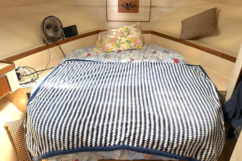 Slide: The Image of Cozy cabin bedroom in a 1990 Bertram 37 Convertible boat with fan and patterned bedding. - 24