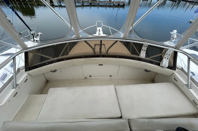 Slide: The Image of 1990 Bertram 37 Convertible boat interior with cushioned seating and water view. - 12