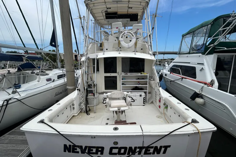 Slide: The Image of 1990 Bertram 37 Convertible boat docked, featuring spacious deck and fishing chair. - 4
