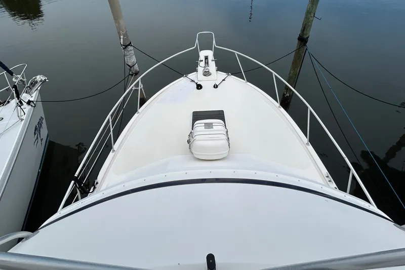Slide: The Image of Bow view of a 1990 Bertram 37 Convertible yacht docked at a marina. - 15