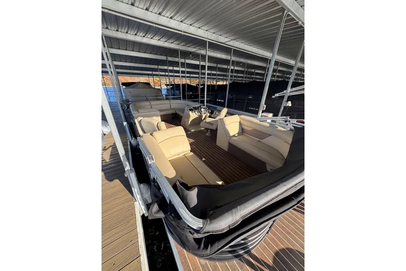 The Image of 2020 Crest Classic LX 220 L pontoon boat with beige seating, docked under a metal canopy. - 0