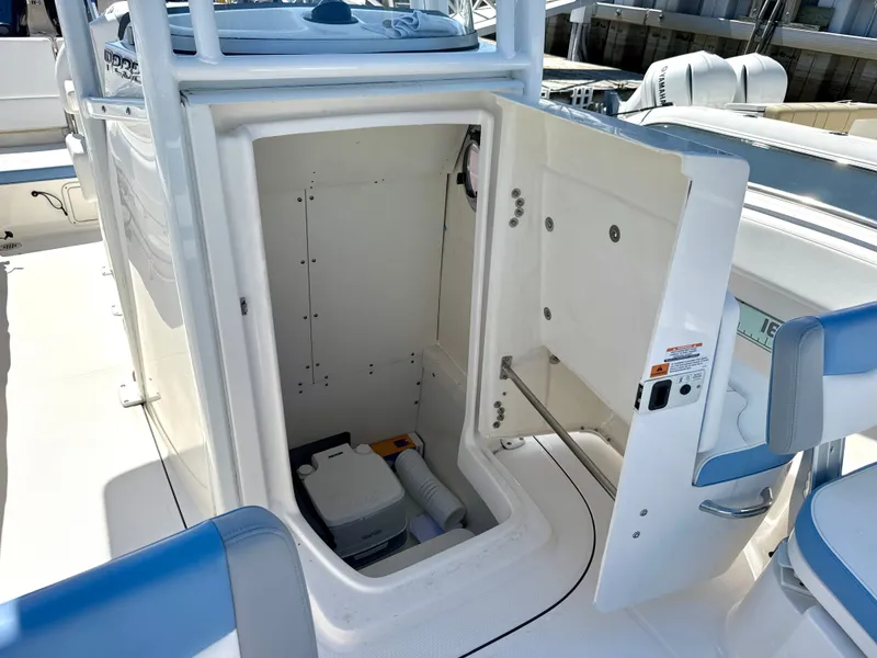 Slide: The Image of The image shows the storage compartment of a 2025 Robalo R232 Explorer boat with an open door. - 12