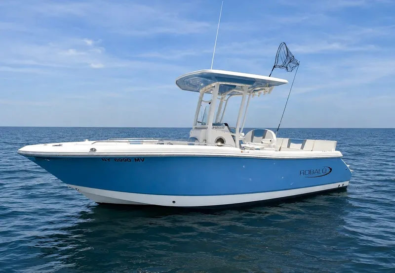 The Image of A blue and white 2025 Robalo R232 Explorer on calm water with a clear sky. - 0