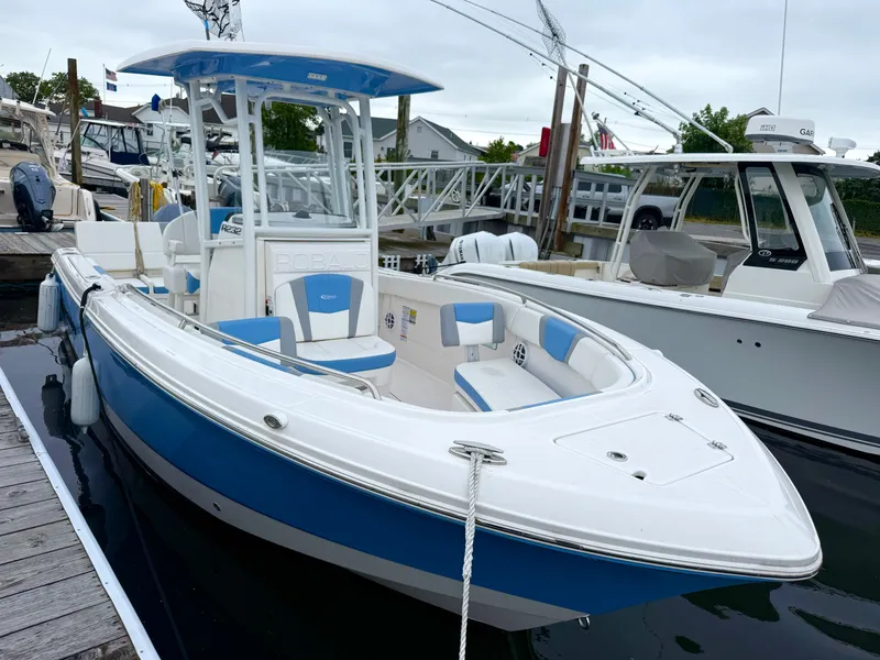 Slide: The Image of The image shows a blue and white Robalo R232 Explorer boat from 2025 docked at a pier. - 3